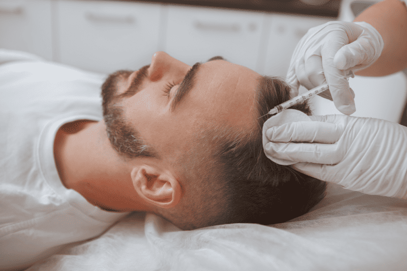 Portfolio 6 Cosmetologist holding syringe and man's head in hands Getting Hair Restoration treatment | Glam Bar Medical Spa in Los Angeles CA
