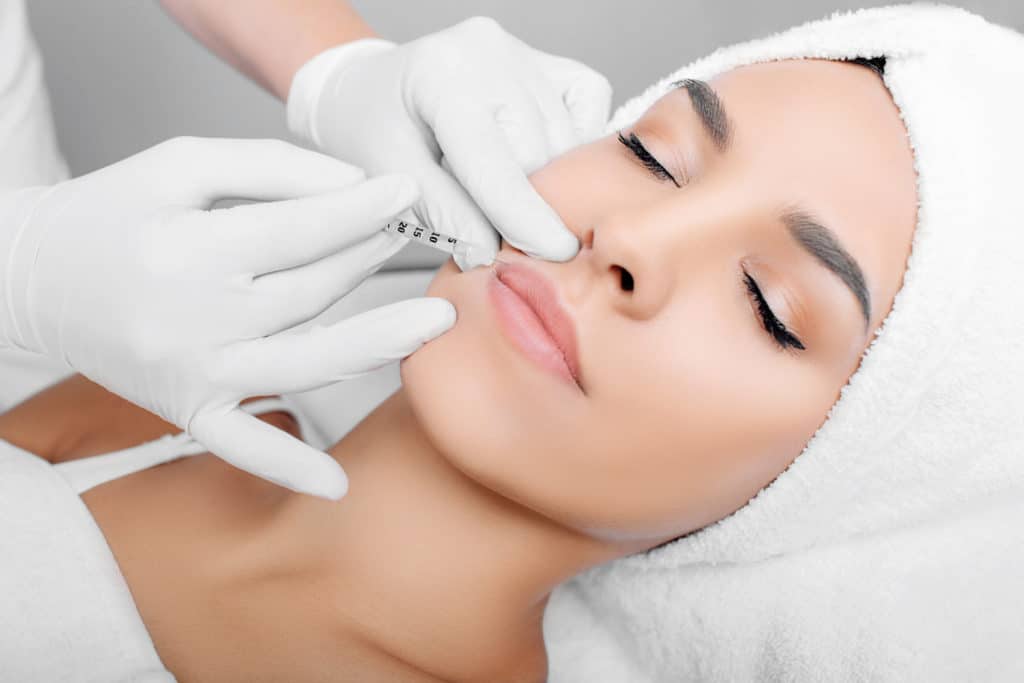 Portfolio 9 woman having lip injections, a prick of a syringe for the beauty lips. lip augmentation | Glam Bar Medical Spa in Los Angeles CA