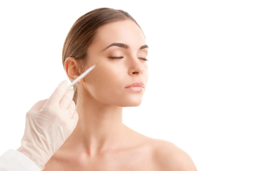 Portfolio 6 Portrait of an attractive young woman receiving botox treatment. Isolated on white background - Woman at plastic surgery | Glam Bar Medical Spa in Los Angeles CA